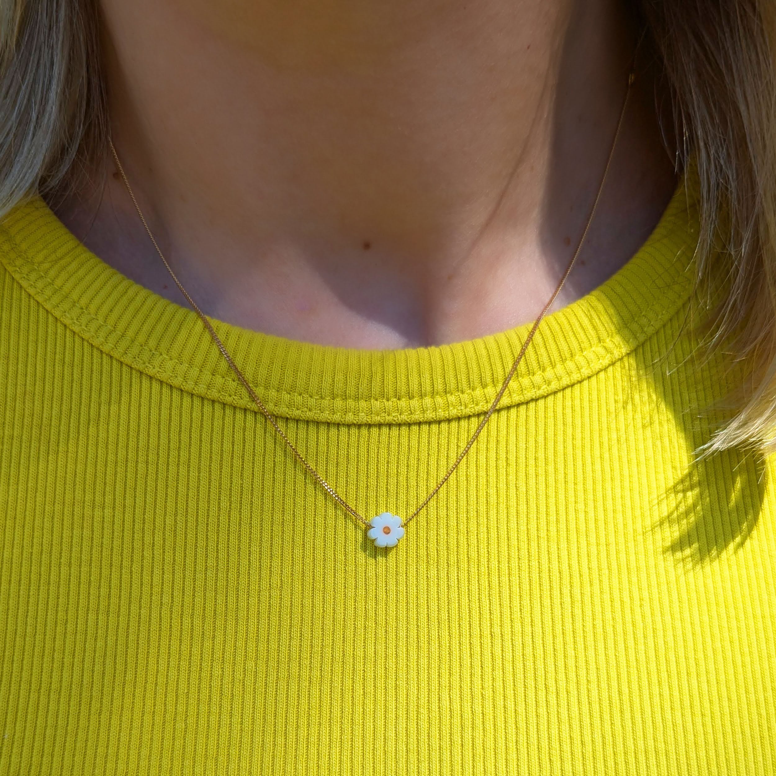 Daisy pendant on fine gold chain being worn