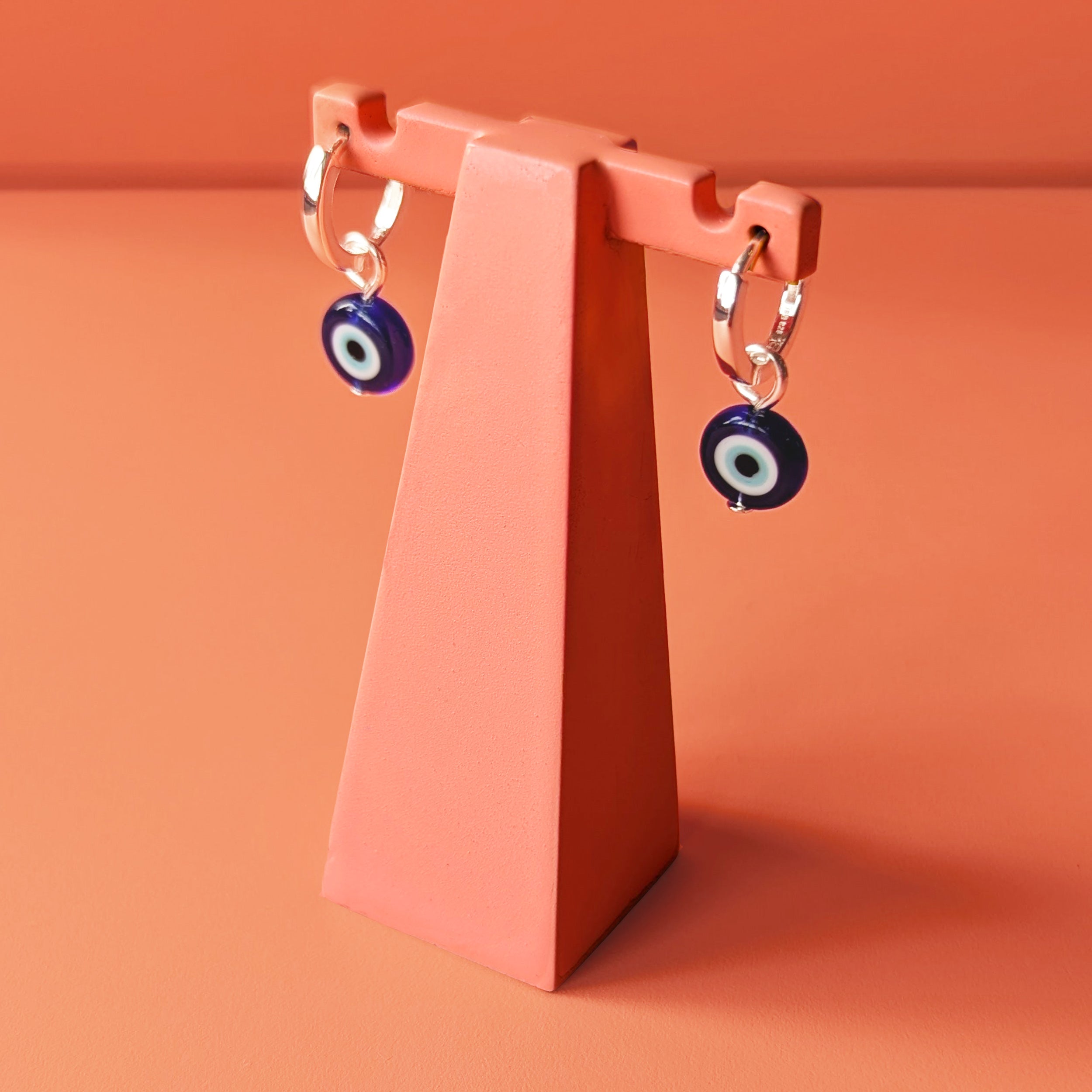 Evil eye charm on silver huggie hoops