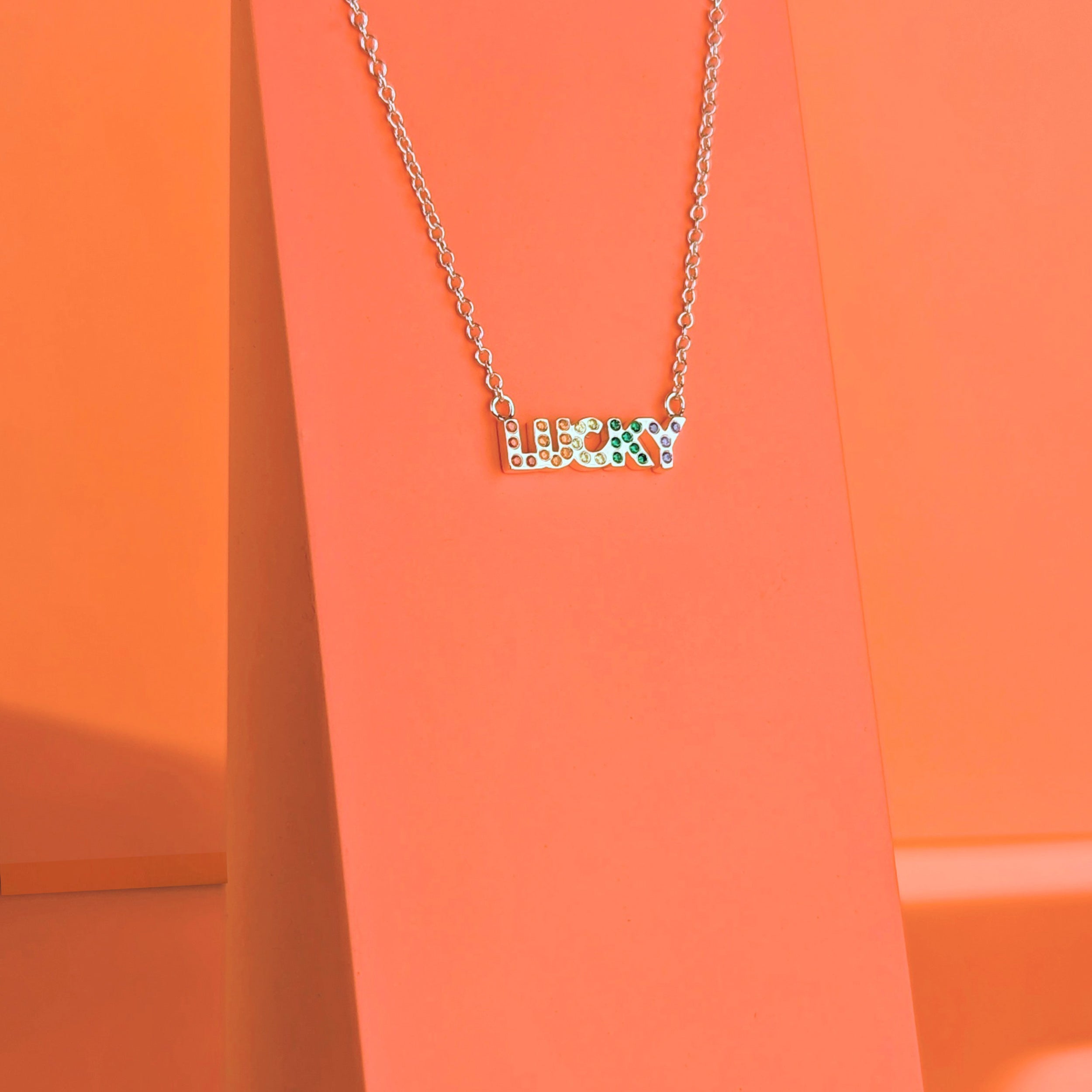 Silver Lucky Gemstone Rainbow Necklace on a coral background